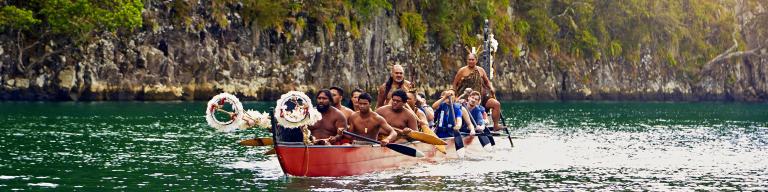 Travellers and locals paddling in a Maori Waka canoe - Maori Culture Tours