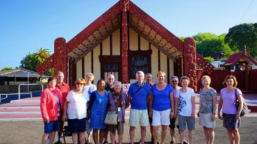Group photo in front of Ohinemutu Marae meeting house, Rotorua - NZ Sightseeing Tour